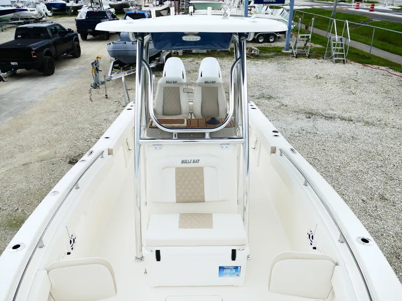 Slide: The Image of 2026 Bulls Bay 255CC boat interior with dual seats and center console, parked on gravel. - 46