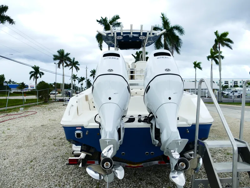 Slide: The Image of 2026 Bulls Bay 255CC boat with dual outboard motors, parked on gravel near palm trees. - 5
