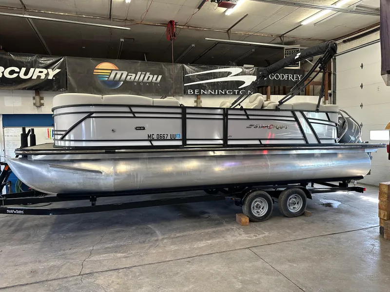 The Image of 2022 Starcraft SLS 3 pontoon boat in a showroom, on a trailer. - 1