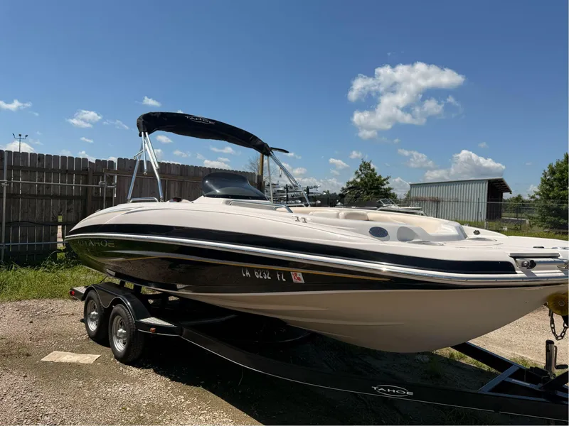 Slide: The Image of 2012 Tahoe 195 boat on trailer, parked outdoors under clear blue sky. - 2