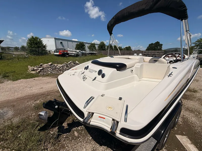 Slide: The Image of 2012 Tahoe 195 boat with canopy, parked outdoors on gravel, under a clear blue sky. - 5