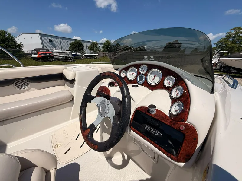 Slide: The Image of 2012 Tahoe 195 boat dashboard with steering wheel and gauges under clear blue sky. - 7