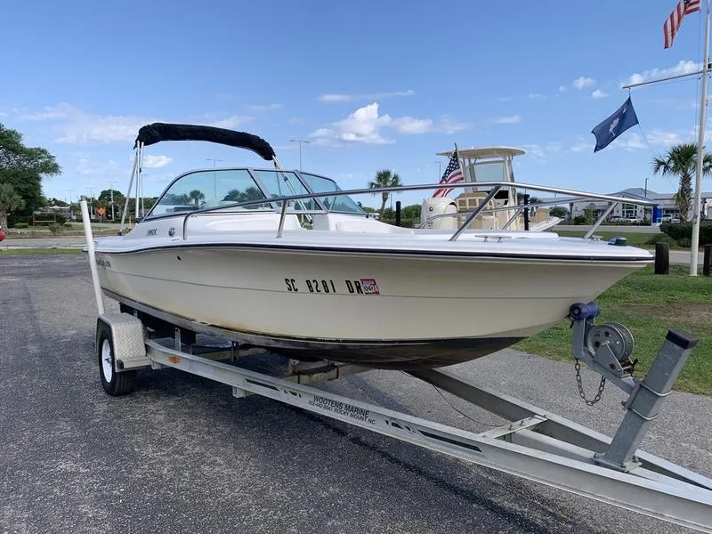 Slide: The Image of 2005 Sailfish 198 DC boat on trailer, parked outdoors under a clear sky. - 6