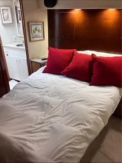 Slide: The Image of 1986 Egg Harbor 60 Sportfisherman cabin with bed, red pillows, and adjacent bathroom. - 13