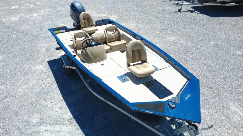 Slide: The Image of 2025 G3 Sportsman 1710 boat with beige seats and blue trim on gravel surface. - 1