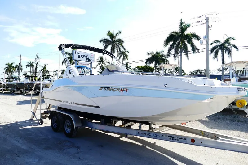 The Image of 2026 Starcraft SVX 211 OB boat on trailer, displayed outdoors with palm trees. - 0