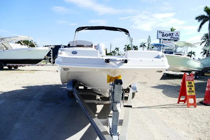 Slide: The Image of 2026 Starcraft SVX 211 OB boat on trailer at dealership, sunny day, palm trees in background. - 9