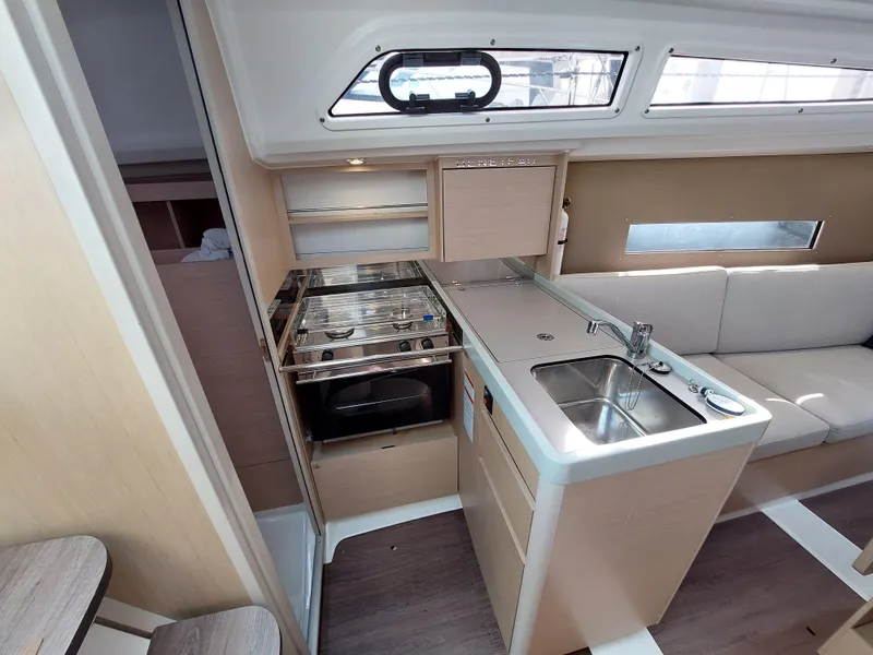 Slide: The Image of Interior of 2020 Beneteau Oceanis 30.1 yacht, featuring a compact kitchen and seating area. - 27