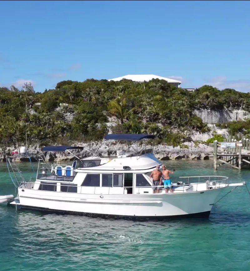 Slide: The Image of 1982 Albin 43 yacht anchored in clear turquoise waters near a lush, green shoreline. - 2