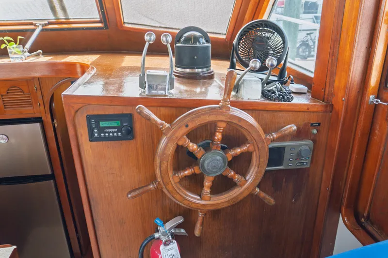 Slide: The Image of 1982 Albin 43 boat helm with wooden wheel, controls, and navigation equipment. - 41