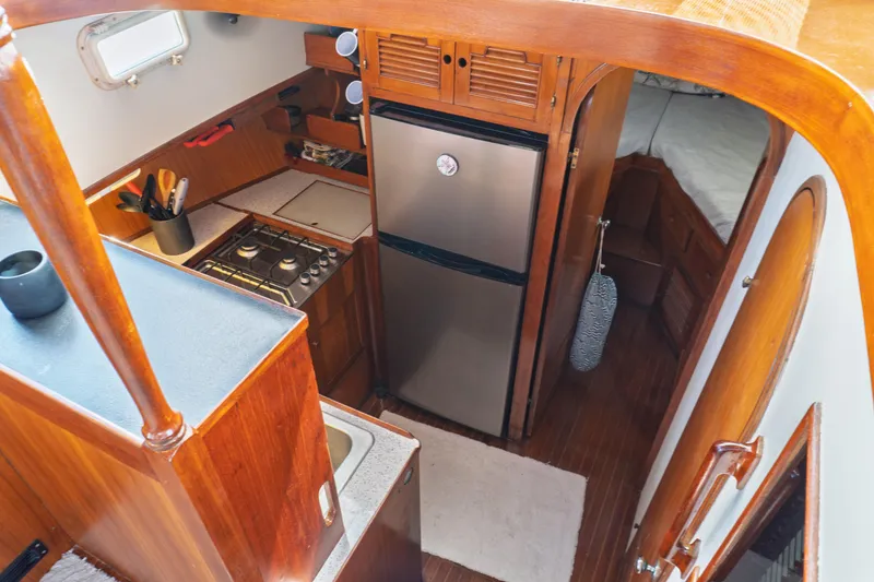 Slide: The Image of Interior of 1982 Albin 43 yacht featuring kitchen with stove, fridge, and wooden cabinetry. - 52