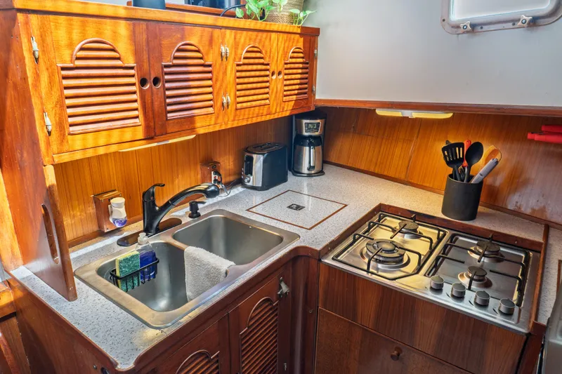 Slide: The Image of 1982 Albin 43 yacht kitchen with wooden cabinets, dual sink, and gas stove. - 55