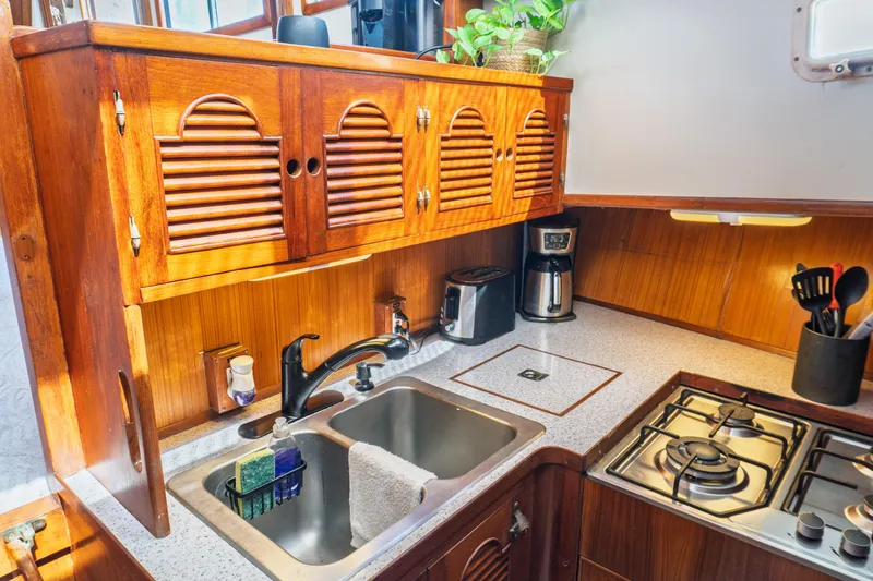 Slide: The Image of 1982 Albin 43 yacht kitchen with wooden cabinets, sink, stove, and appliances. - 56