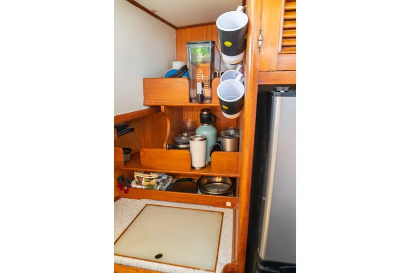 Slide: The Image of Compact kitchen area in a 1982 Albin 43 boat with wooden shelves and kitchenware. - 61