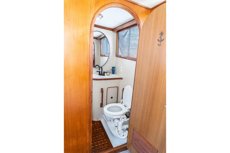Slide: The Image of 1982 Albin 43 yacht bathroom with wooden accents, toilet, and sink. - 79