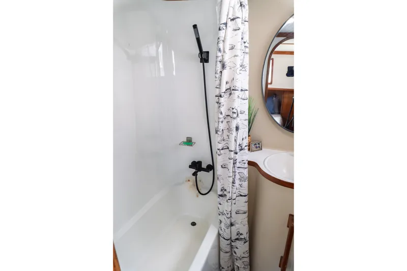 Slide: The Image of 1982 Albin 43 yacht bathroom with shower, nautical curtain, and round mirror. - 82
