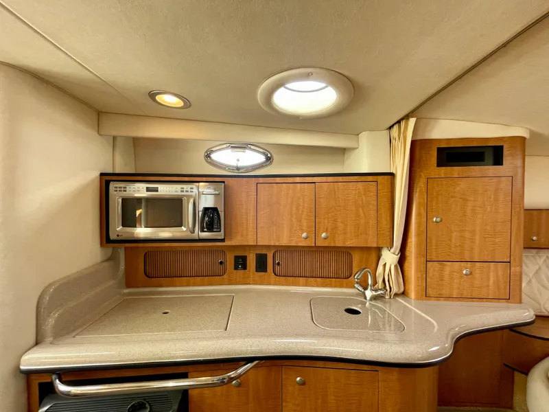 Slide: The Image of 2006 Sea Ray 320 Sundancer interior kitchen with microwave, coffee maker, and wooden cabinetry. - 14