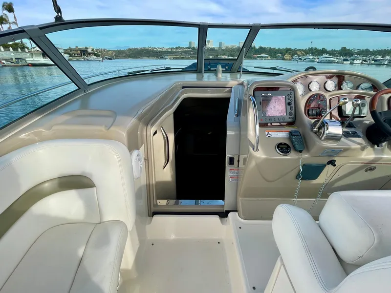 Slide: The Image of 2006 Sea Ray 320 Sundancer cockpit with navigation controls and seating, overlooking marina. - 25