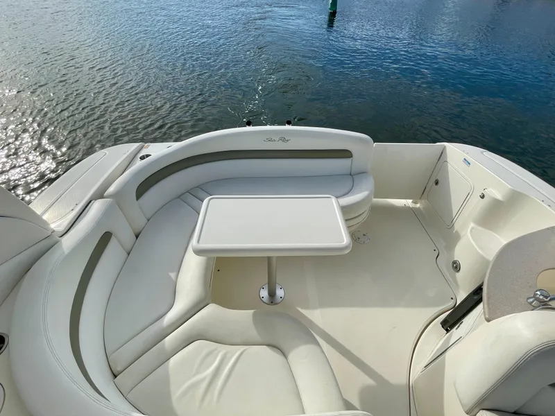 Slide: The Image of 2006 Sea Ray 320 Sundancer boat interior with white seating and table, near water. - 30