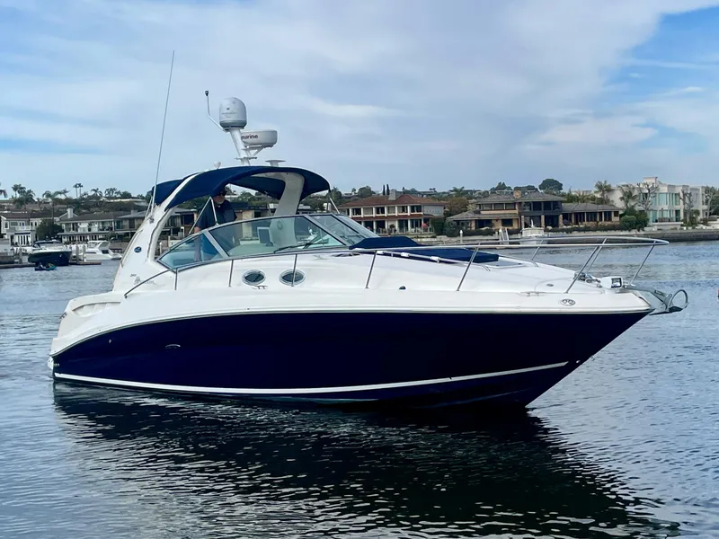 Slide: The Image of 2006 Sea Ray 320 Sundancer yacht on calm water, with coastal homes in the background. - 4