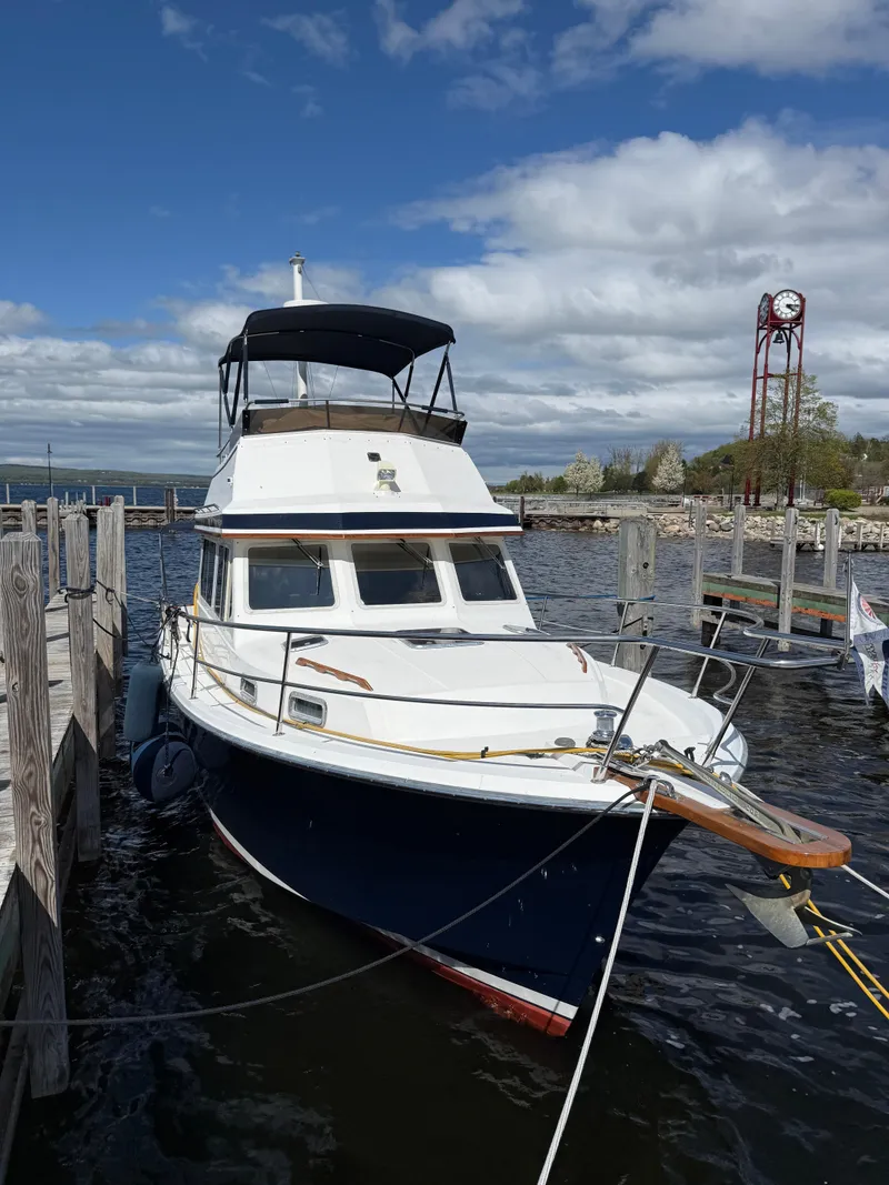 Slide: The Image of 1999 Sabreline 34 Flybridge boat docked at a marina under a cloudy sky. - 13
