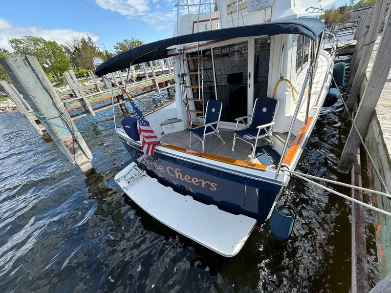 Slide: The Image of Sabreline 34 Flybridge 1999 docked, featuring a spacious deck with chairs and an American flag. - 18
