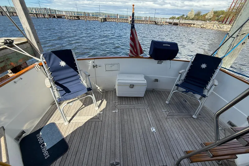 Slide: The Image of 1999 Sabreline 34 Flybridge deck with chairs, cooler, and American flag by the water. - 19