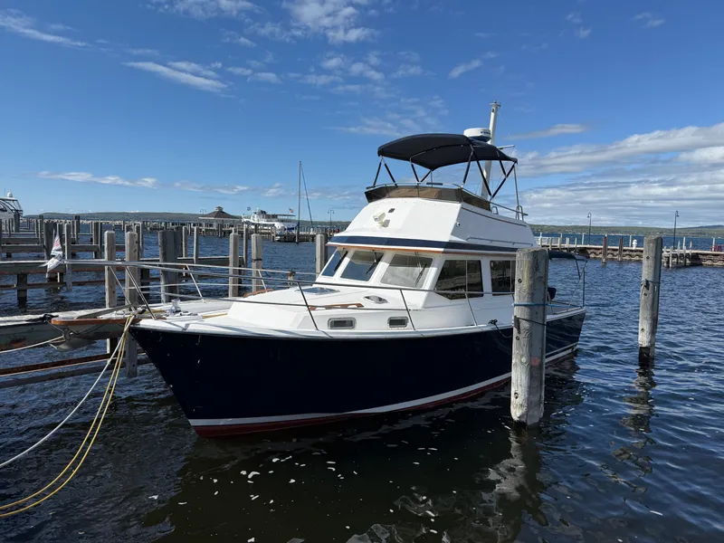 Slide: The Image of 1999 Sabreline 34 Flybridge boat docked at marina under clear blue sky. - 2