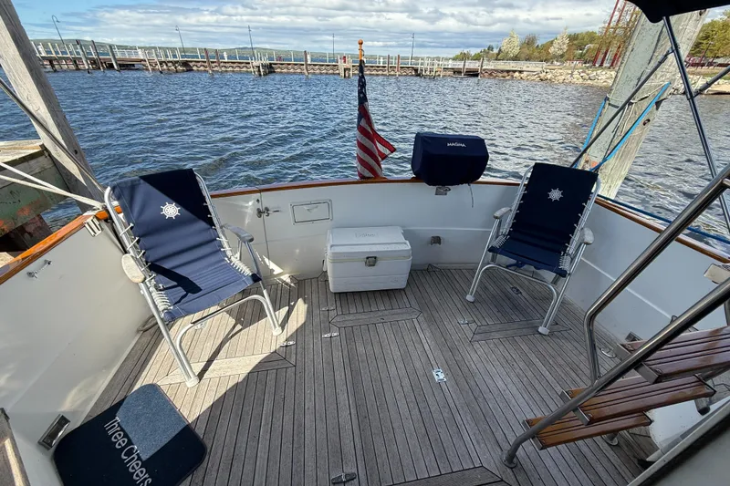 Slide: The Image of 1999 Sabreline 34 Flybridge deck with chairs, cooler, and American flag by the water. - 20
