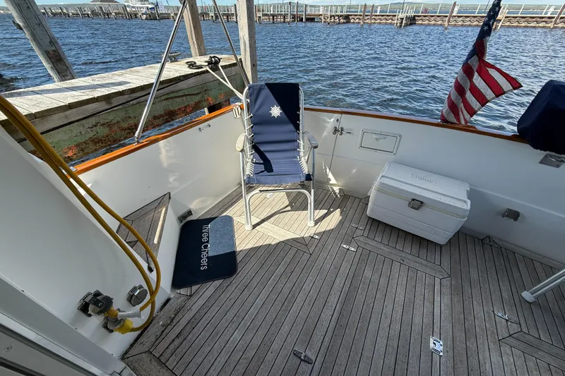 Slide: The Image of 1999 Sabreline 34 Flybridge deck with chair, cooler, and American flag by the water. - 22