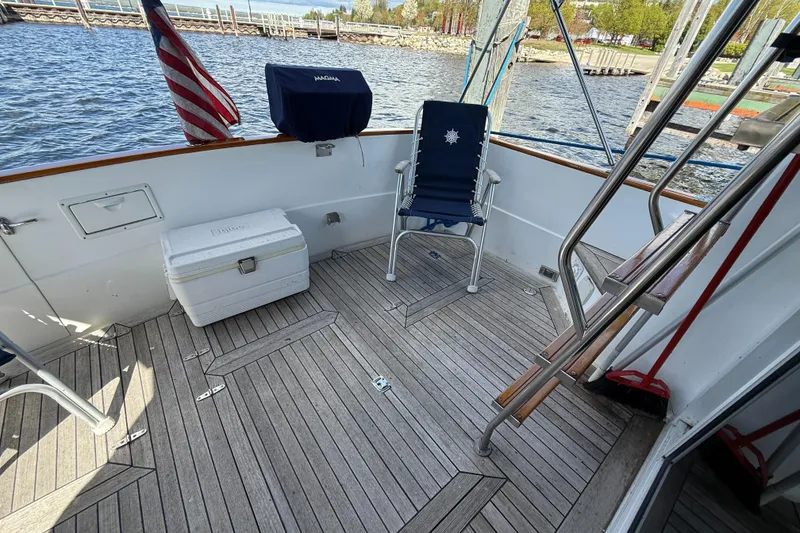 Slide: The Image of 1999 Sabreline 34 Flybridge deck with chair, cooler, and American flag by the water. - 23