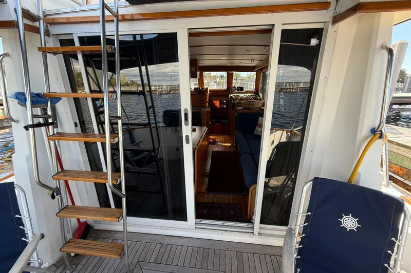 Slide: The Image of 1999 Sabreline 34 Flybridge yacht with wooden steps and glass doors, docked by the water. - 25