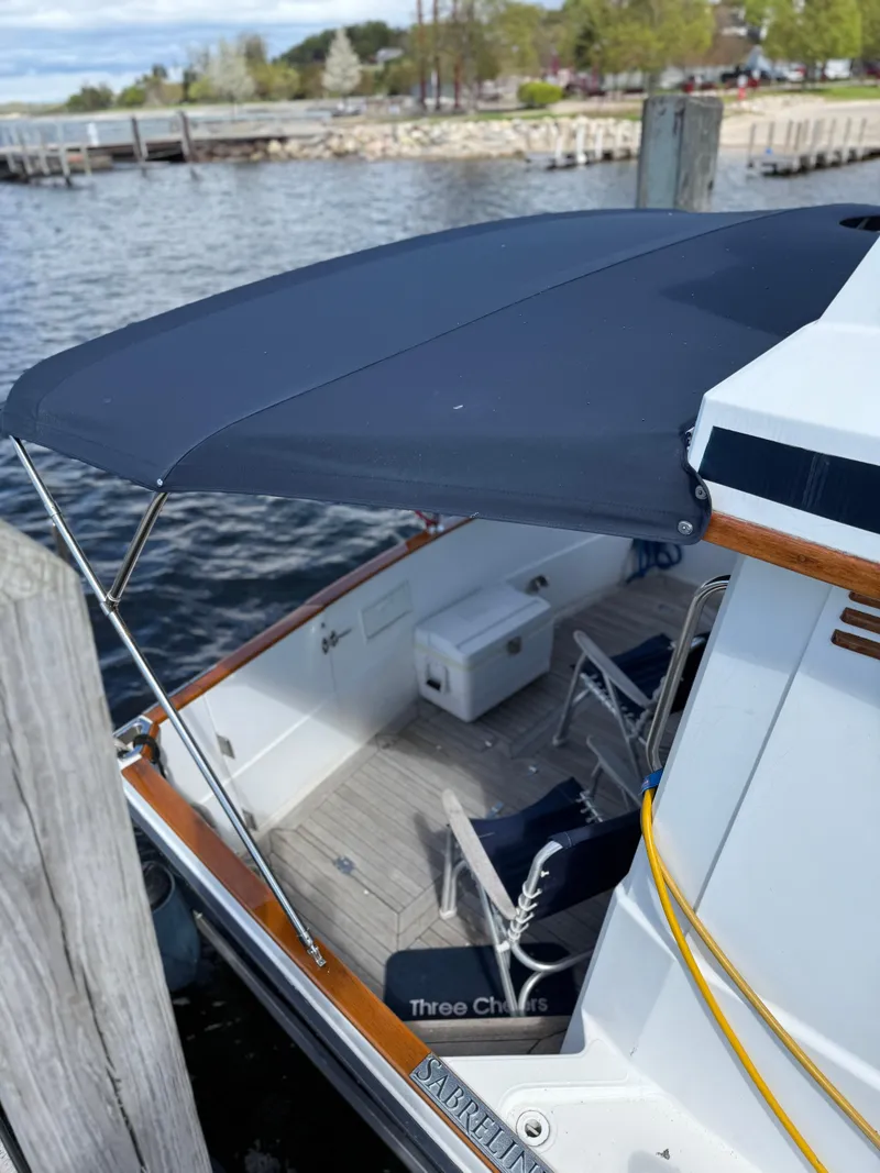 Slide: The Image of 1999 Sabreline 34 Flybridge docked, featuring a shaded deck with seating and storage. - 26