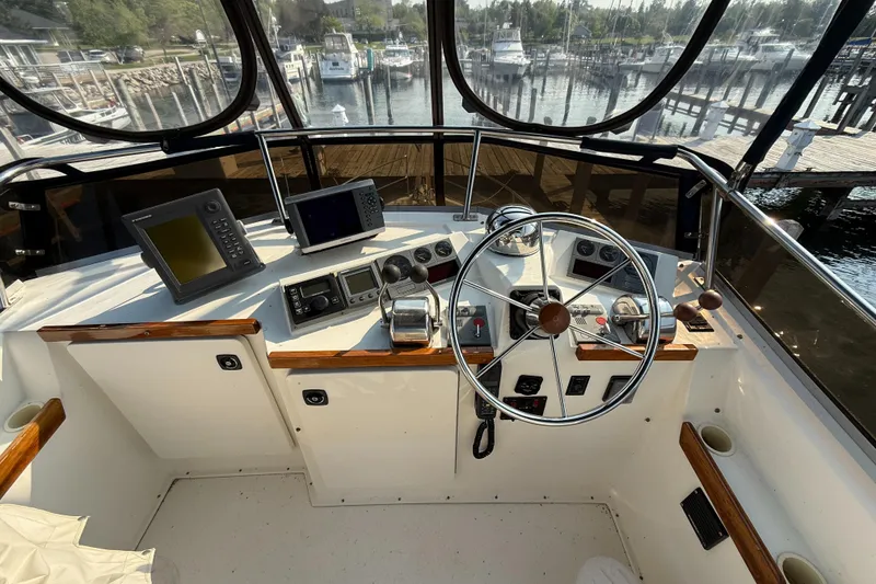 Slide: The Image of 1999 Sabreline 34 Flybridge helm with steering wheel, navigation equipment, and marina view. - 34