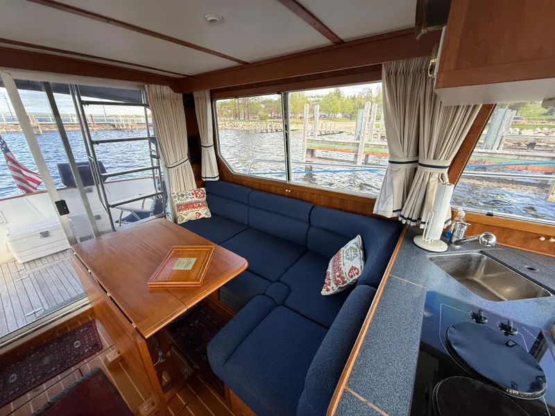 Slide: The Image of Interior of 1999 Sabreline 34 Flybridge with blue seating, wooden table, and waterfront view. - 43