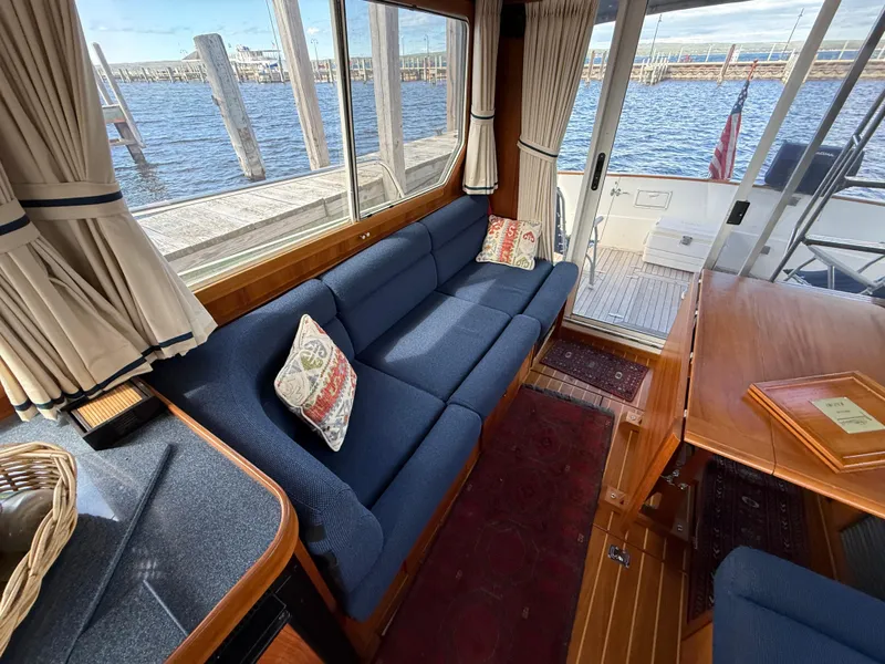 Slide: The Image of Interior of 1999 Sabreline 34 Flybridge with blue sofa, wooden table, and waterfront view. - 44