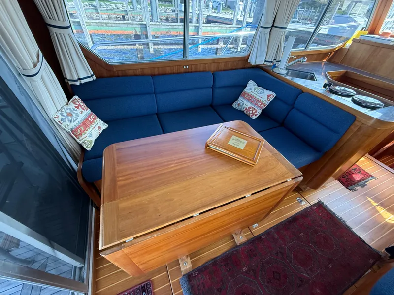 Slide: The Image of 1999 Sabreline 34 Flybridge interior with blue seating, wooden table, and decorative pillows. - 47