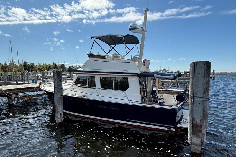 Slide: The Image of 1999 Sabreline 34 Flybridge boat docked at a marina under a clear blue sky. - 6