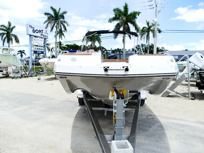 Slide: The Image of 2026 Starcraft SVX 231 OB boat on trailer at dealership, surrounded by palm trees. - 4