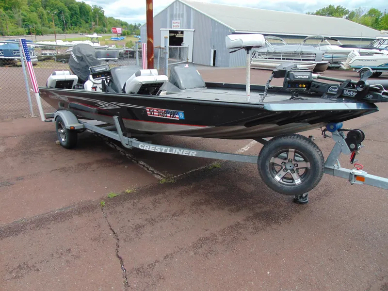 Slide: The Image of 2014 Crestliner VT 19 boat on trailer, parked outdoors near a warehouse. - 1