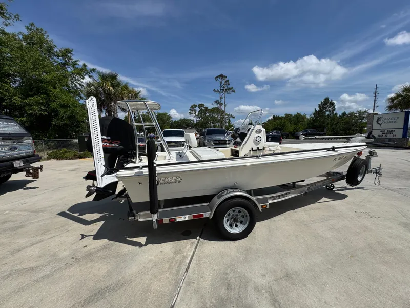 Slide: The Image of 2021 Hewes Redfisher 18 boat on trailer, parked outdoors under a clear blue sky. - 11