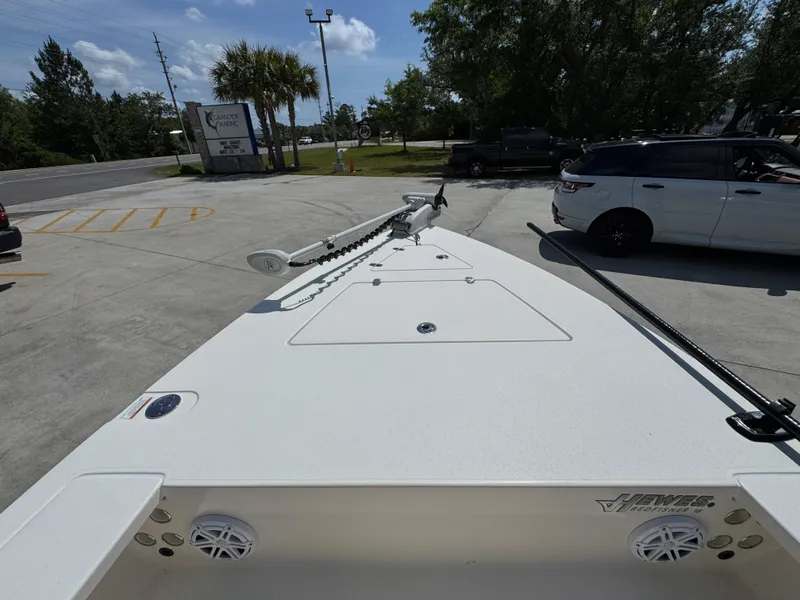 Slide: The Image of 2021 Hewes Redfisher 18 boat parked in a lot, showcasing its deck and trolling motor. - 22