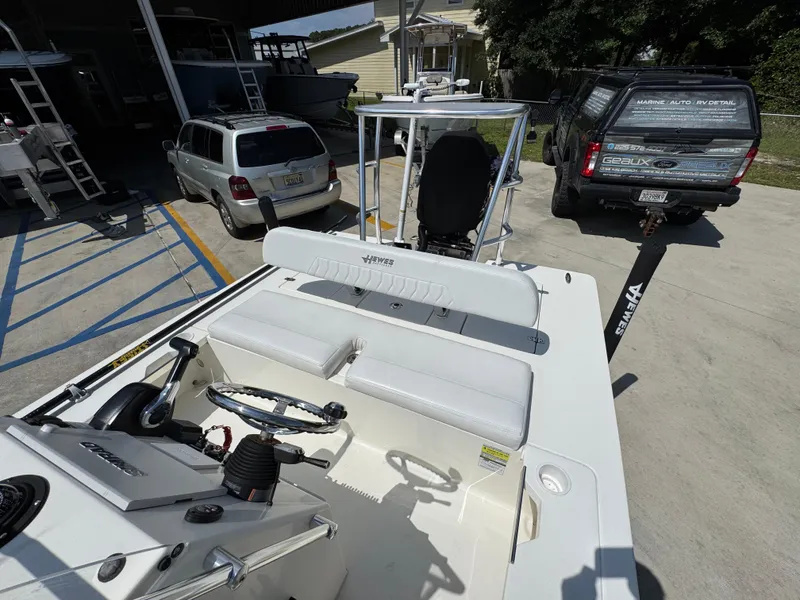 Slide: The Image of 2021 Hewes Redfisher 18 boat interior with steering wheel and seating, parked near vehicles. - 35