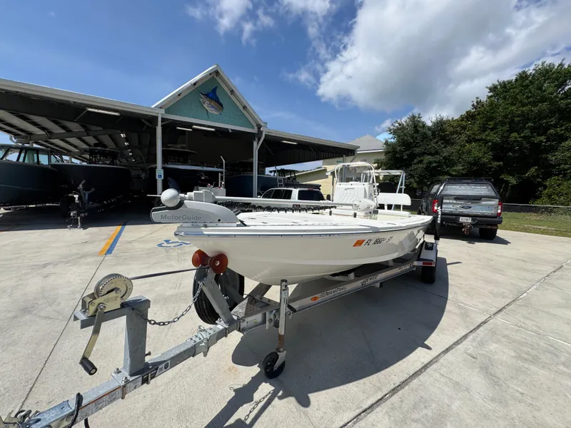 Slide: The Image of 2021 Hewes Redfisher 18 boat on trailer, parked outdoors under a partly cloudy sky. - 4