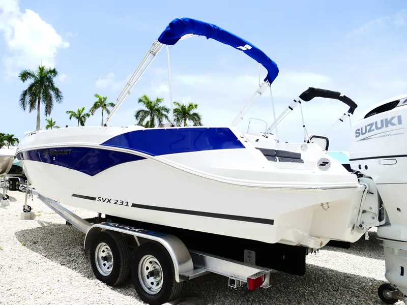 The Image of 2026 Starcraft SVX 231 OB DH boat on trailer, blue and white design, palm trees in background. - 0