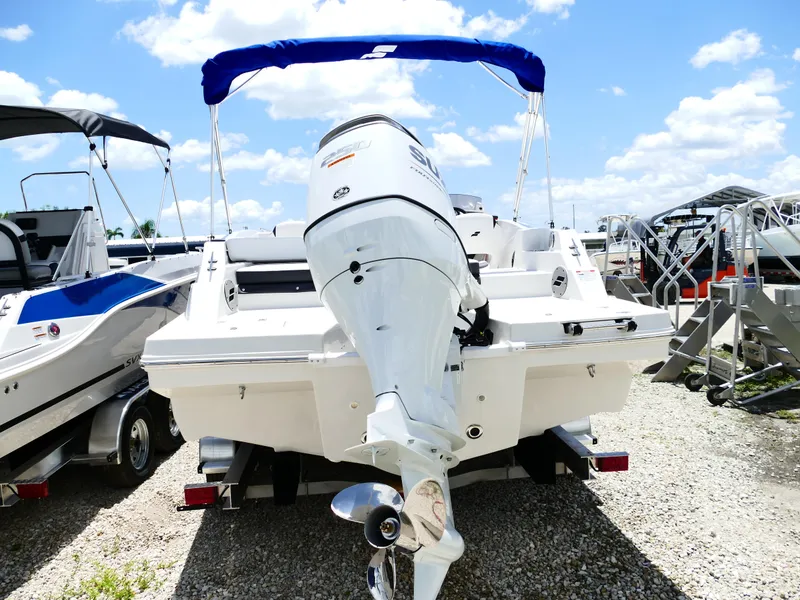 Slide: The Image of 2026 Starcraft SVX 231 OB DH boat with outboard motor, parked on gravel under blue sky. - 10