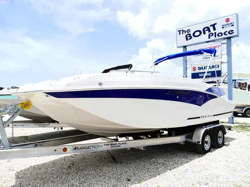 Slide: The Image of 2026 Starcraft SVX 231 OB DH boat on trailer at dealership, clear sky background. - 2