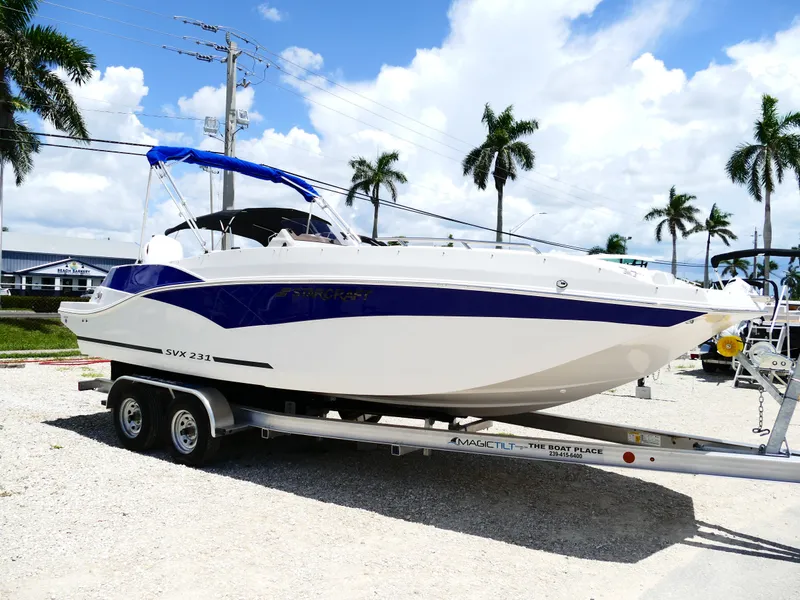 Slide: The Image of 2026 Starcraft SVX 231 OB DH boat on trailer, parked outdoors under blue sky. - 8
