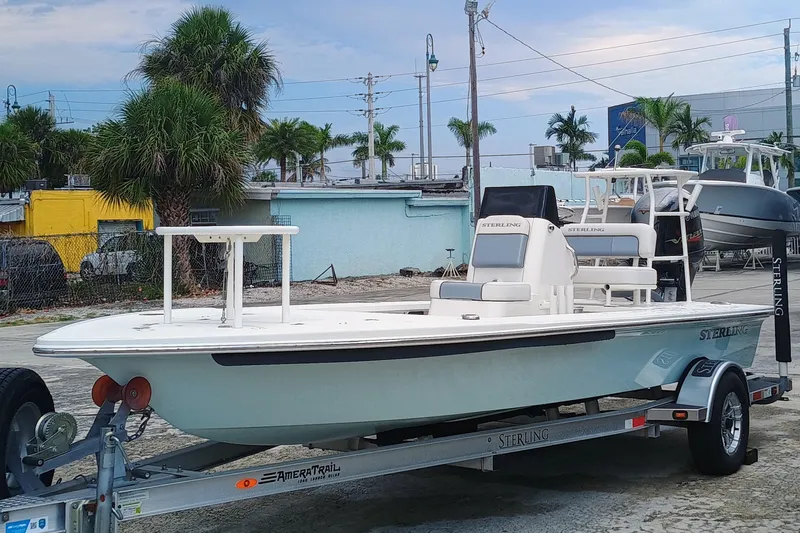 Slide: The Image of 2023 Sterling 180TS boat on trailer, parked outdoors with palm trees in background. - 2