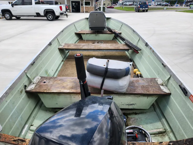 Slide: The Image of 1970 Starcraft Aluminum boat interior with motor, wooden seats, and equipment on a concrete surface. - 4